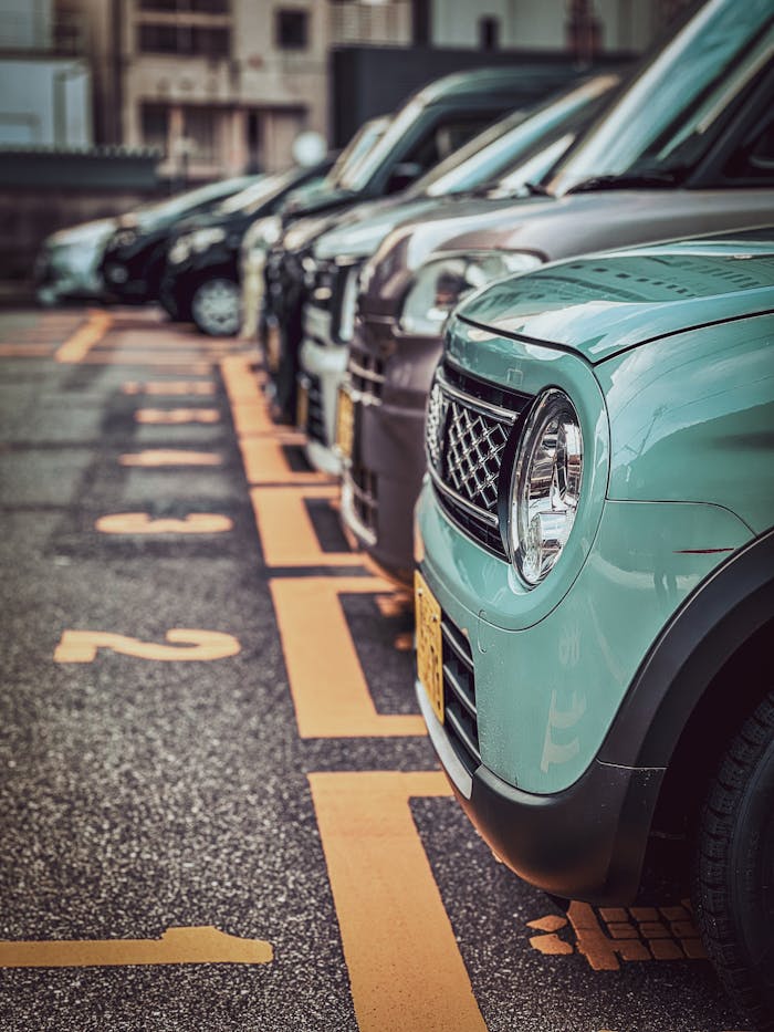 Service A row of parked cars in an urban parking lot with numbered spaces, showcasing a focus on one green car.