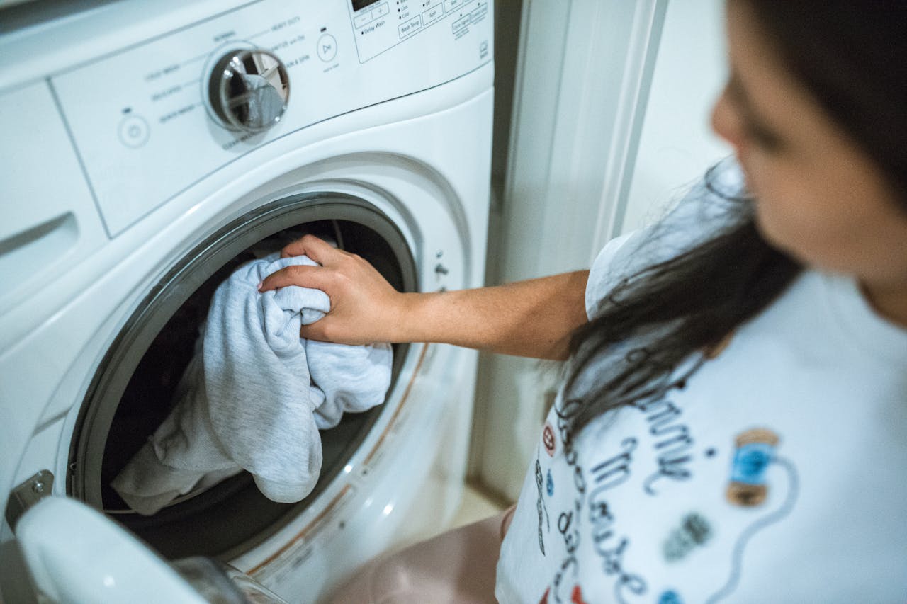 About A woman loading laundry into a washing machine indoors, focusing on household chores.